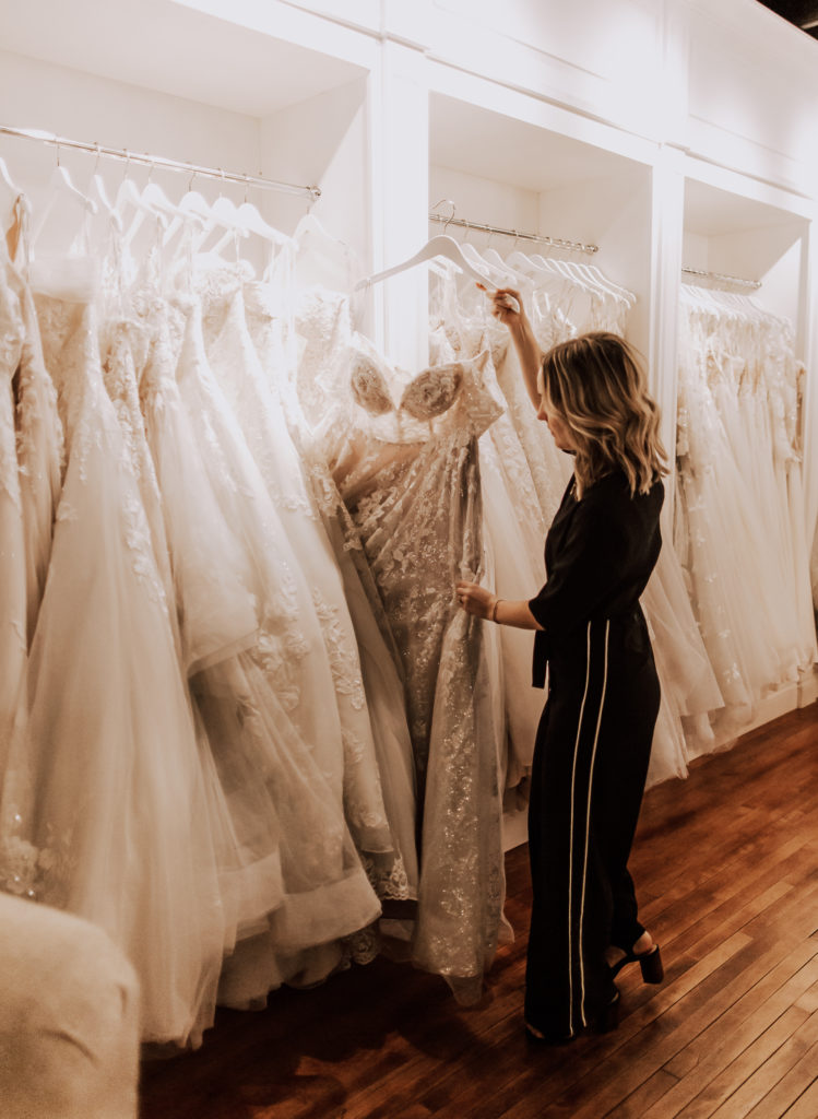 Bridal consultant picking a dress from the rack of bridal gowns