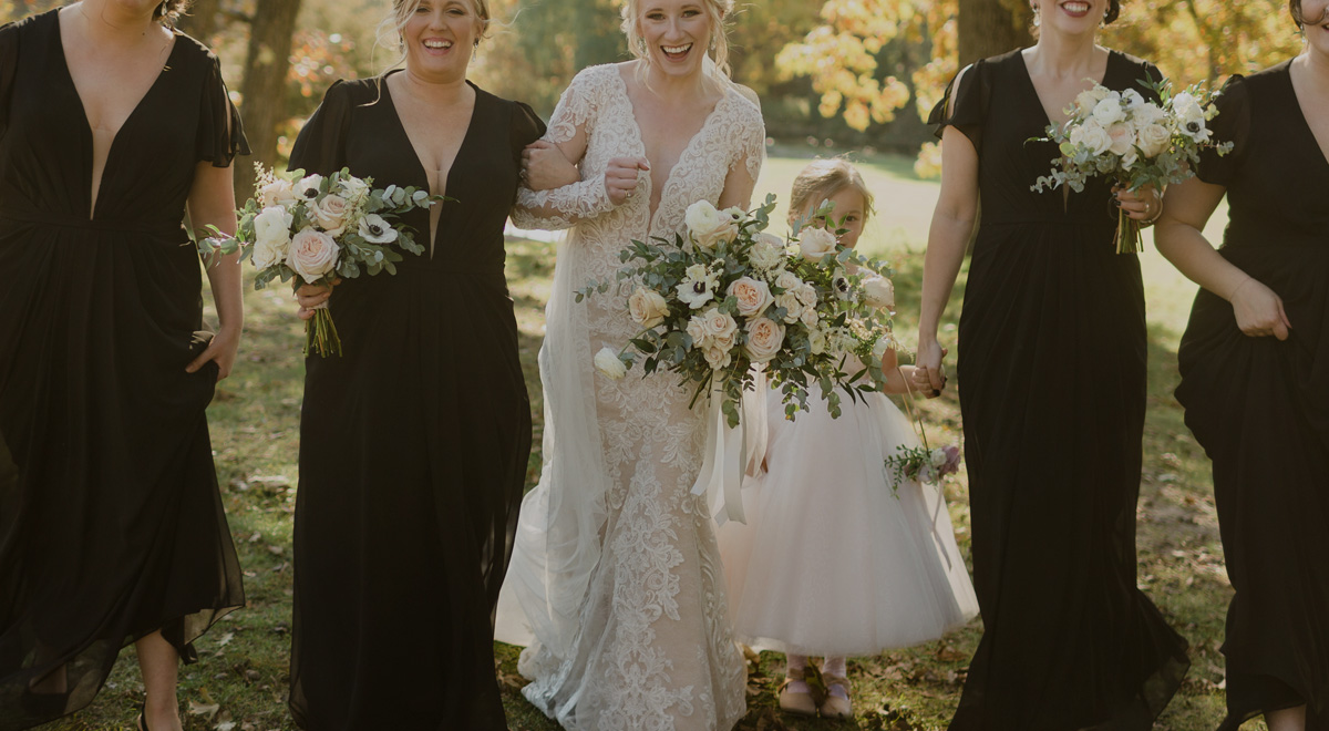 Image of bride with bridesmaids in their dresses from marien mae holding bouquets of flowers smiling